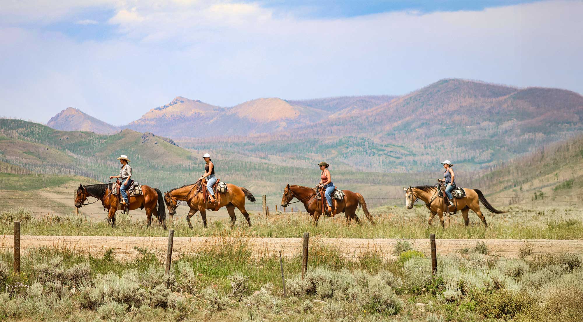 Two kids and two adults out for a trail ride on horseback during summertime at C Lazy U Ranch